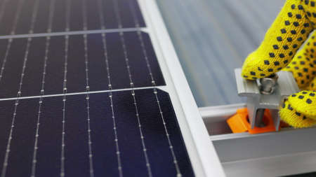 Mounting solar panel, installing solar panels on the roof of the house. Connection of solar panels. Close up of worker installing and working on maintenance of photovoltaic panel system installed.の写真素材
