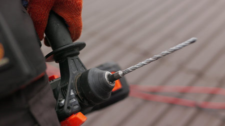 Unrecognizable construction worker on a construction site, holding a work tool, drill or power tools...