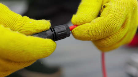 An electrician checks the wires. Special wire hardener at the power plant. An electrician in protective gloves installs wires. Connection of soy panelsの写真素材