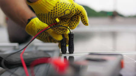 Close up, Solar energy specialist monitoring solar panels with his multimeter. Alternative, green energy worker. Energy engineer monitoring solar panels with his multimeter. Solar energy concept.の写真素材