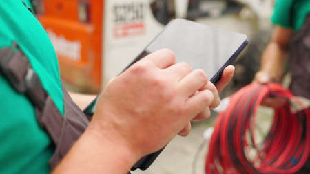 Electrical worker engineer a working with digital tablet, power near tower with electricity. energy business technology industry concept. electrical engineer studying reading on tablet.の写真素材