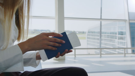 Close-up, Woman holds air tickets and passports in her hands against the backdrop of empty check-in counters at the airport. Travelling by airplane. Ticket documents for boarding plane trainの写真素材