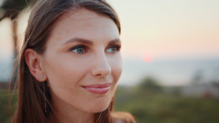Close up portrait of stunning young woman with long brown hair and blue eyes posing on ocean beach. Sporty female relaxation during evening training on fresh air.の写真素材