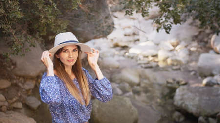 Portrait, Charming caucasian woman wearing summer hat and clothes walking among high rocks and looking around. Female tourist discovering new place during summer adventure. Charming woman in summer.の写真素材