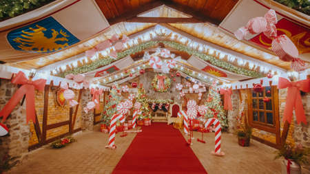 Christmas big house of Santa Claus, lots of Christmas trees and candies. The Christmas house is decorated with lights. Christmas Tree with Decorations and Gifts Near a Fireplace with Lights.の写真素材