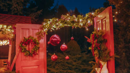 Beautiful house decorated for Christmas is about Christmas trees. Open the door of the house for Santa Claus. Christmas night. Christmas holiday wreath adorns front door to home.の写真素材