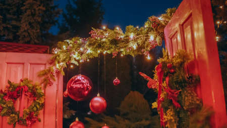 Beautiful house decorated for Christmas is about Christmas trees. Open the door of the house for Santa Claus. Christmas night. Christmas holiday wreath adorns front door to home.の写真素材