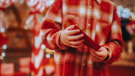 Unrecognizable child holding a decorated letter for Santa Claus. Decorated Christmas letter in the hands of a little boy. Christmas celebration concept.の写真素材