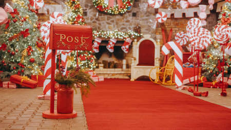 Santa Claus workshop, wrapped gifts presents boxes on holiday eve in night on xmas background. Red post box for letters to Lapland to Santa Claus. Christmas tradition. Decorative mailbox.の写真素材
