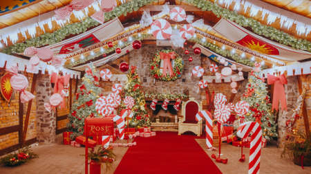 Red post box for letters to Lapland to Santa Claus. Christmas tradition. Decorative mailbox Santa Claus workshop, wrapped gifts presents boxes on holiday eve in night on xmas backgroundの写真素材