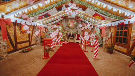 Luxurious red chair Santa Claus throne surrounded by multiple gift boxes. Decorative mailbox Santa Claus workshop, wrapped gifts presents boxes on holiday eve in night on xmas backgroundの写真素材