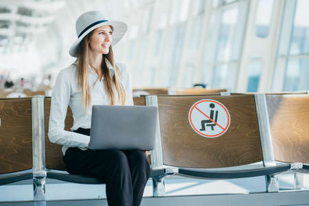 Teenage girl is using a laptop to check email or social network or internet at the international airport to travel on weekendsの写真素材