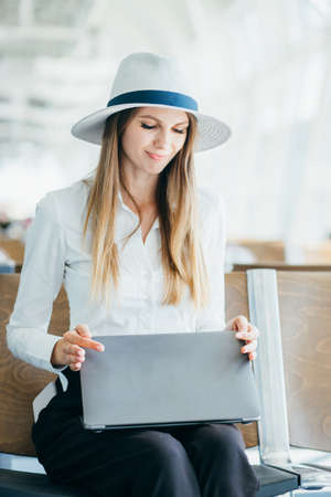 Beauty woman using laptop with suitcase while waiting for take off flight. Woman sitting in airport terminal. People and lifestyle concept. Technology and travel theme. Portrait theme.の写真素材