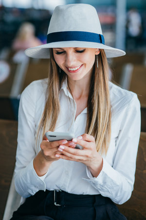 Woman walking in airport and looking at mobile phone.の写真素材