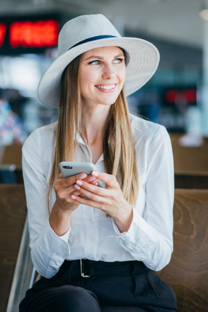 Airport business woman waiting in terminal. Air travel concept with casual businesswoman sitting with suitcase. Mixed race female professionsの写真素材