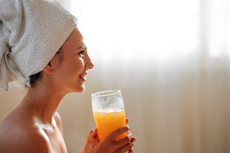 Woman have breakfast in modern hotel apartment. Window light portrait young girl in bathrobe lying on bed using laptop for work. Out of focus tray with meal, juice, plate, teapot on background.の写真素材