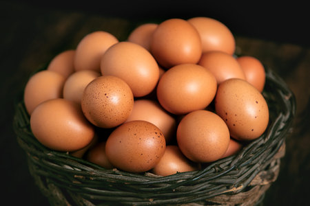 Bunch of eggs in a basket on a wooden old retro table with black backgroundの写真素材
