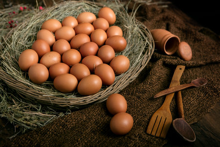 Eggs in a wooden basket full of hay on a rustic old tabletopの写真素材