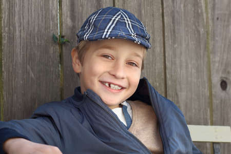 Cute smiling boy in his hat and blue coat, outdoorの写真素材