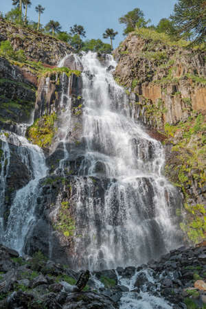 Close-up vertical shot of waterfall with vegetation on the sides in southern Chileの写真素材