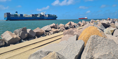 Container ship leaving and arriving at the port between two breakwaters