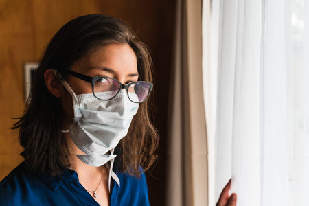 woman with face mask looking out the window
