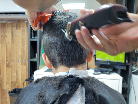 Photo of a boy getting a haircut, with a clipper, photographed from behindの写真素材
