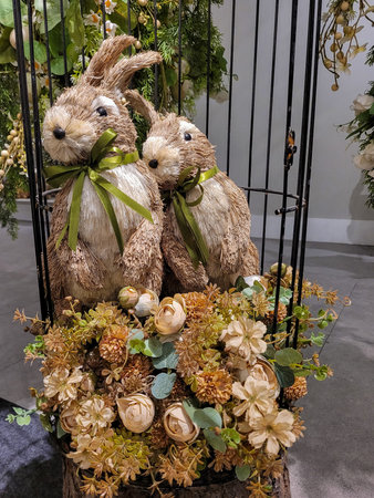 Decorative Easter photo, with two rustic straw rabbits, on top of flowers. Photo captured in...