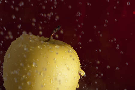 A golden apple with water drops fallingの写真素材