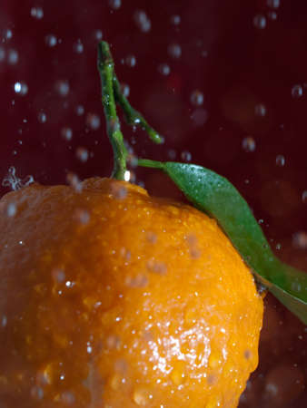 A tangerine with some water drops fallingの写真素材
