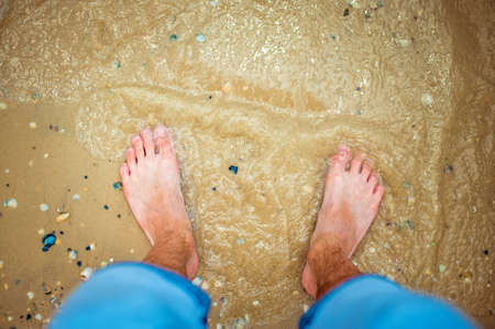 The guy looks at his feet in the sea.の写真素材