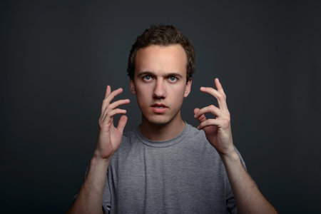 Portrait closeup funny confused skeptical man thinking looking up isolated on gray wall background with copy space above head. Human face expressions, emotions, feelings, body languageの写真素材