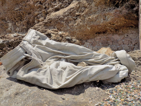 Rolled up pants that were taken and left on a rock.の写真素材