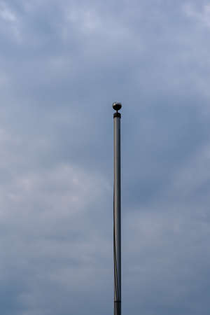 an empty flagpole against a dark sky with cloudsの写真素材
