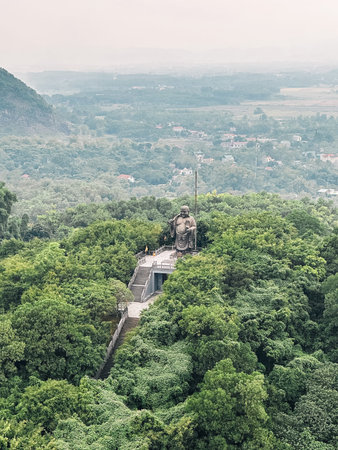 Large Buddha statue in the middle of the rainforest in the Bai Dinh temple complex on a foggy day in...