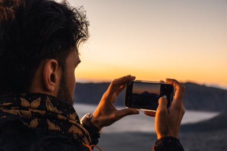 Tourist capturing memories through a photography of moon like landscape of Bromo volcano at sunrise with a dramatic sky in Java, Indonesiaの写真素材
