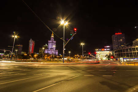 Historical Skyscraper (Palace of Culture and Science) and Clock Tower at the end of a Busy City Street in Downtown Warsaw, Poland (Night)のeditorial素材