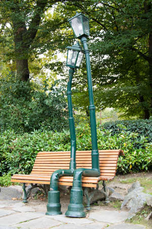 Sculpture of two lampposts resting on a bench in the middle of a parkの写真素材