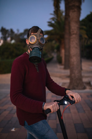 Man in a World War II mask with an e-scooter on the street by covid-19. Concept of health. Caucasian. In the park.の写真素材