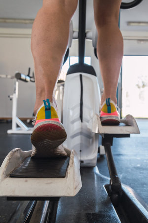 young man working out on an elliptical trainer in gym.