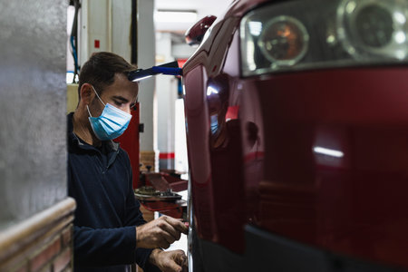 mechanic with mask repairing car wheel. Mechanical concept. Focus on him. COVID19