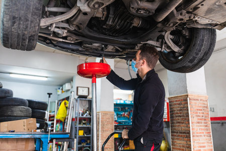 Mechanic with mask changing the oil of the car.の写真素材