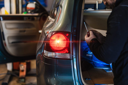 Mechanic repairing car rear light. Electromechanical workshop. Working with his hands. Tools....