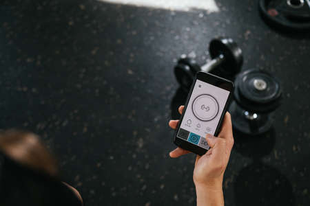 A man with a smart phone in the gym. Looking at the screen of the smart phone. health and wellness concept.の写真素材