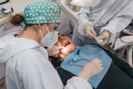 Female dentist with a patient in her office. Patient with open mouth and woman dentist working. dental health concept.の写真素材