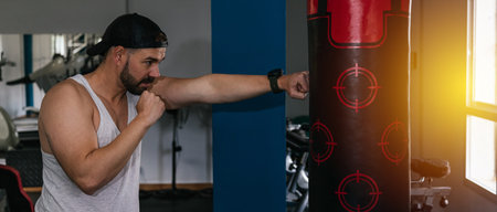 Man punching punching bag in gym. Gym.