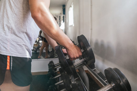 Hand gripping a dumbbell, on a dumbbell bench. Gym. Sports concept