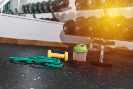 Protein shake and dumbbells at the gym. Fitness nutrition drink and heavy weights.Pの写真素材