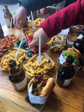 Table with hamburgers and beers. Happy people partying and eating in home garden - Young active...