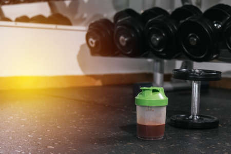 Protein shake and dumbbells at the gym. Fitness nutrition drink and heavy weights.Pの写真素材